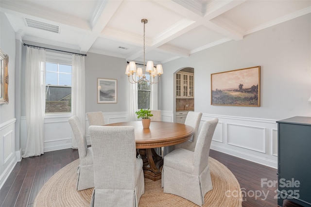 dining area with a decorative wall, dark wood-type flooring, coffered ceiling, visible vents, and beamed ceiling