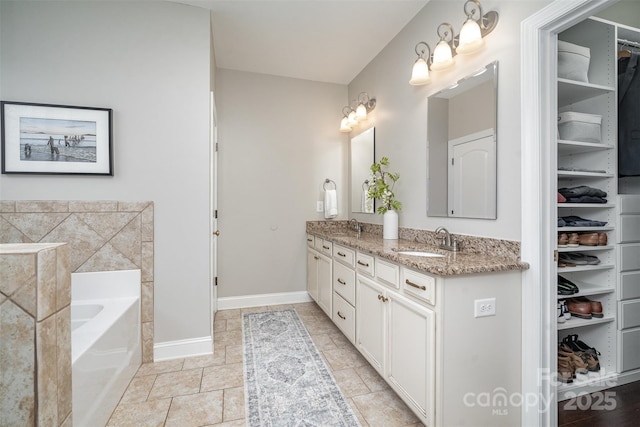 full bath with double vanity, baseboards, a sink, a spacious closet, and a bath