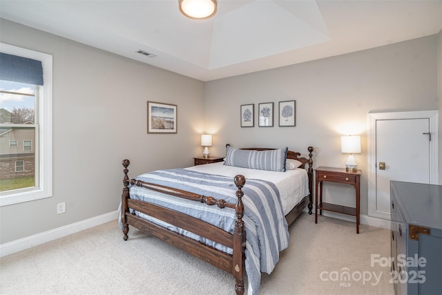 bedroom featuring baseboards, a raised ceiling, visible vents, and light colored carpet