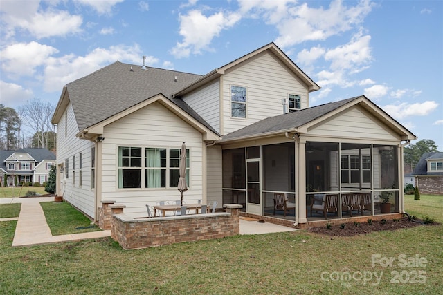 rear view of property featuring a patio area, a sunroom, a lawn, and roof with shingles