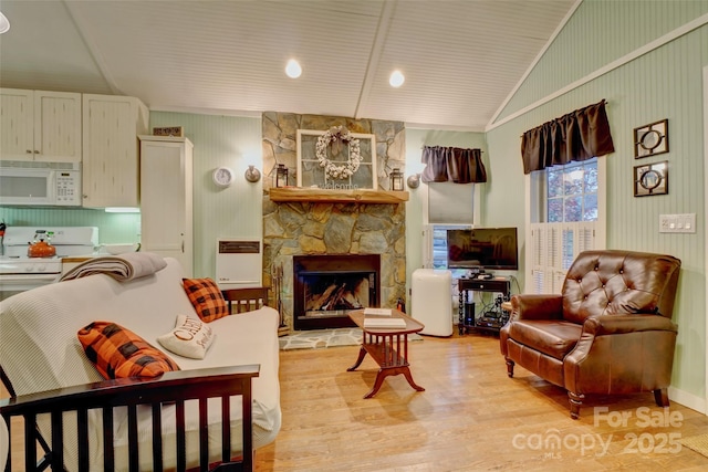 living room featuring lofted ceiling, a fireplace, and light hardwood / wood-style floors