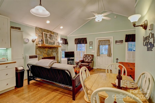 bedroom with vaulted ceiling, ceiling fan, a stone fireplace, and light hardwood / wood-style floors