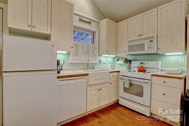 kitchen with white appliances, lofted ceiling, sink, and light hardwood / wood-style flooring