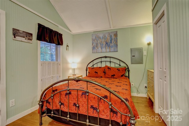 bedroom featuring lofted ceiling, hardwood / wood-style floors, and electric panel