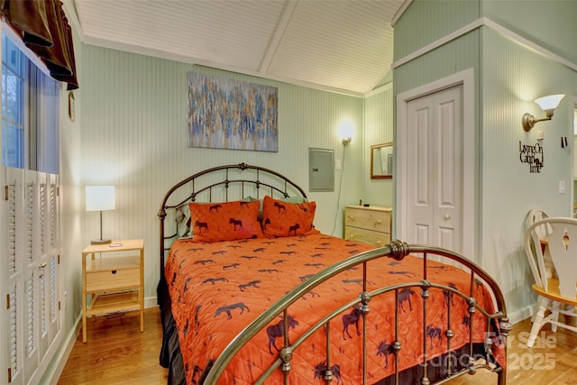 bedroom featuring vaulted ceiling, hardwood / wood-style floors, electric panel, and a closet