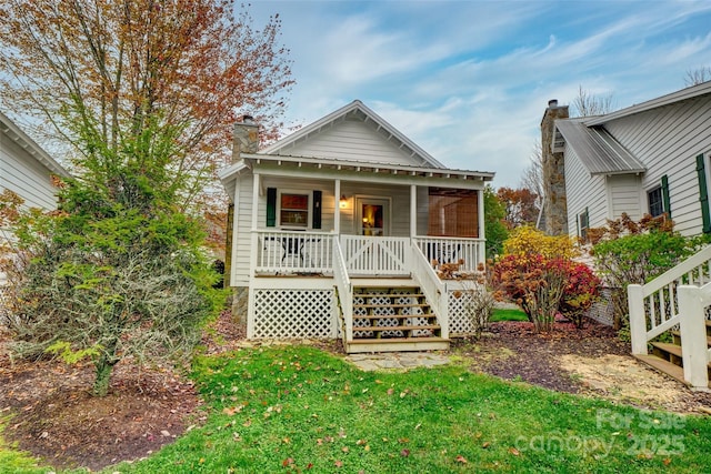 rear view of house with a porch and a lawn