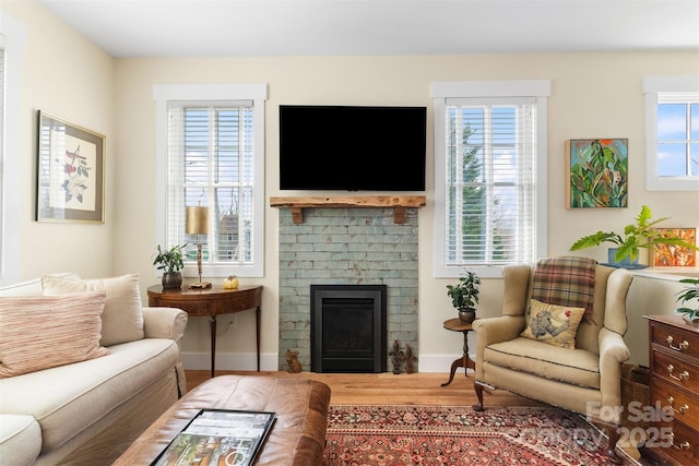 living room featuring a brick fireplace, hardwood / wood-style flooring, and a healthy amount of sunlight