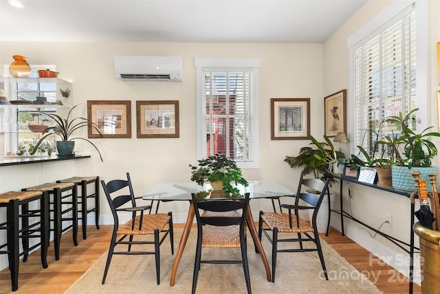 dining area featuring light hardwood / wood-style floors and a wall unit AC