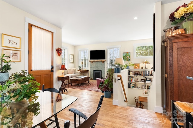 living room featuring a brick fireplace and light wood-type flooring