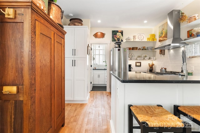 kitchen with white cabinetry, tasteful backsplash, extractor fan, a kitchen bar, and stainless steel gas stovetop