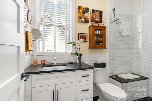 bathroom featuring tile walls, vanity, toilet, and tiled shower