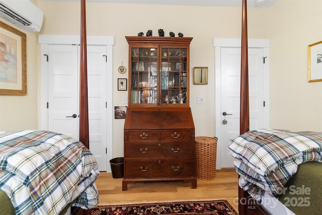 bedroom featuring an AC wall unit and light hardwood / wood-style flooring