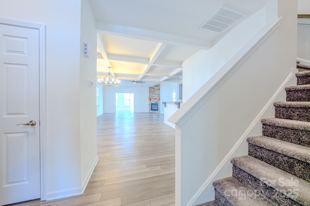 stairs featuring beamed ceiling, wood-type flooring, and coffered ceiling