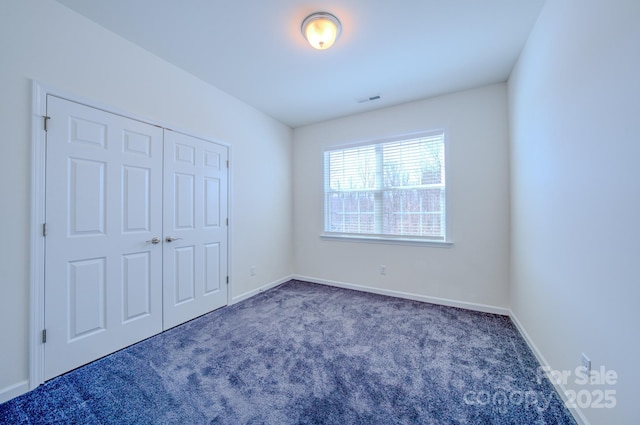 unfurnished bedroom with a closet and dark colored carpet