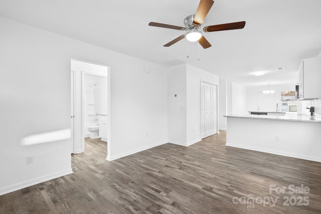 unfurnished living room featuring ceiling fan with notable chandelier and dark hardwood / wood-style flooring