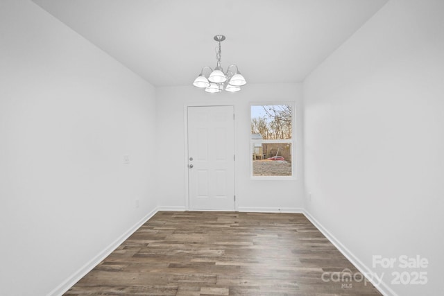 unfurnished dining area with a notable chandelier and dark wood-type flooring