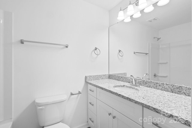 bathroom with vanity, a shower, and toilet