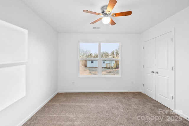 unfurnished room with ceiling fan and carpet