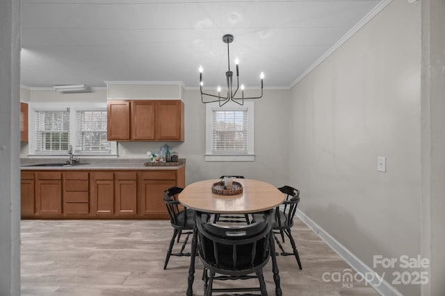 dining space featuring an inviting chandelier, sink, crown molding, and light hardwood / wood-style flooring