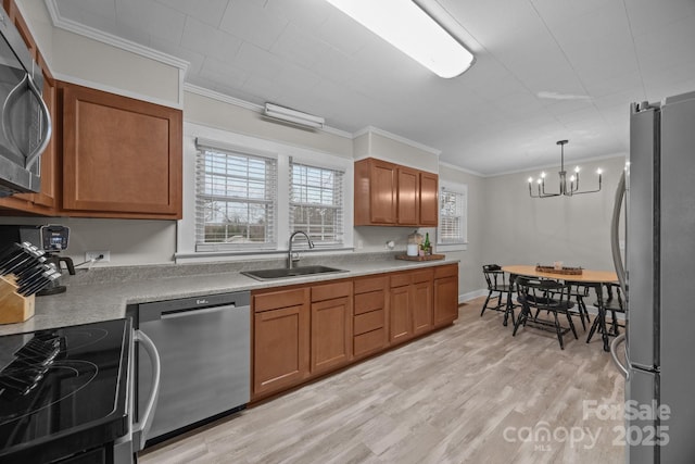 kitchen with appliances with stainless steel finishes, decorative light fixtures, sink, crown molding, and light wood-type flooring