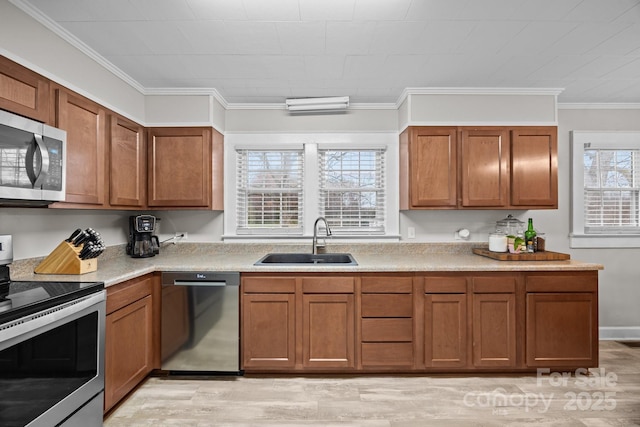 kitchen with stainless steel appliances, ornamental molding, sink, and light hardwood / wood-style floors