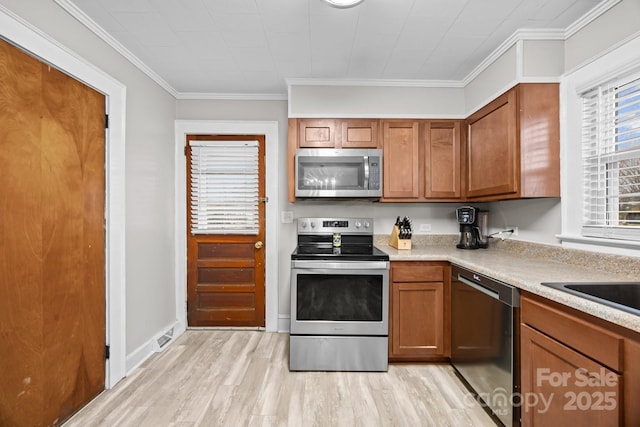 kitchen featuring stainless steel appliances, crown molding, and light hardwood / wood-style floors