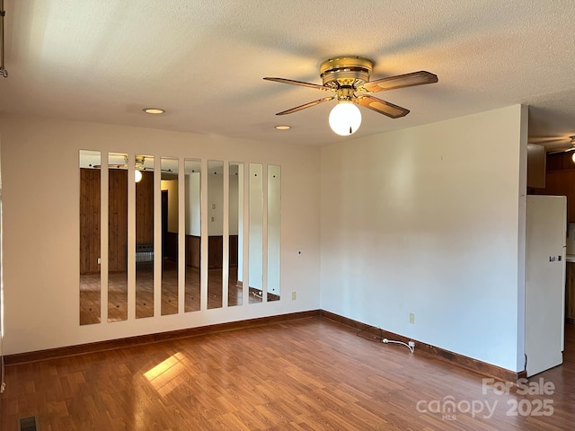 empty room with ceiling fan, hardwood / wood-style floors, and a textured ceiling