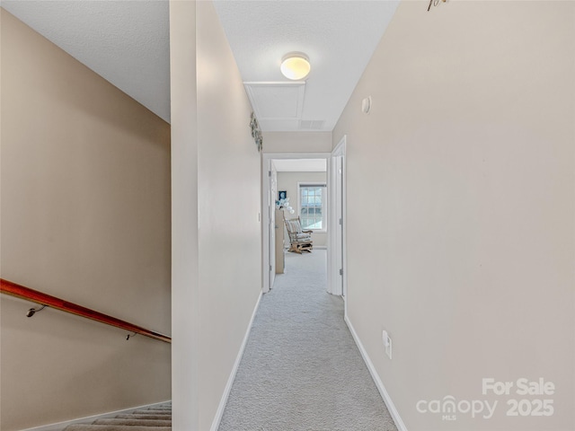 corridor featuring light carpet and a textured ceiling