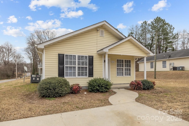 bungalow with a front yard and central air condition unit