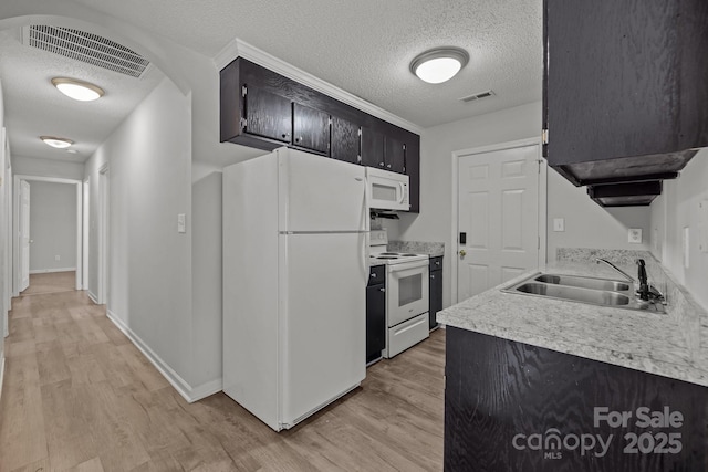 kitchen featuring sink, a textured ceiling, white appliances, and light hardwood / wood-style flooring