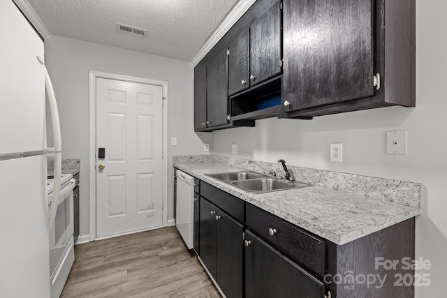 kitchen featuring white appliances, sink, a textured ceiling, and light wood-type flooring