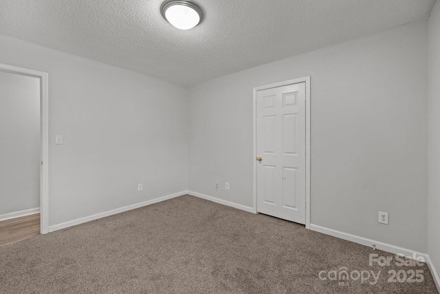 empty room with carpet floors and a textured ceiling