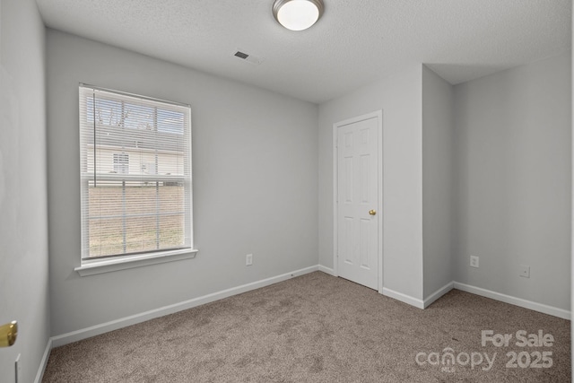 carpeted spare room with a textured ceiling