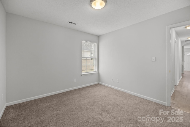 carpeted empty room featuring a textured ceiling