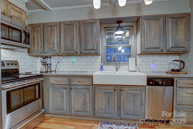 kitchen with ornamental molding, appliances with stainless steel finishes, sink, and backsplash