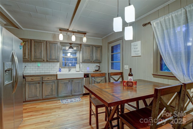 dining area featuring ornamental molding, sink, and light wood-type flooring