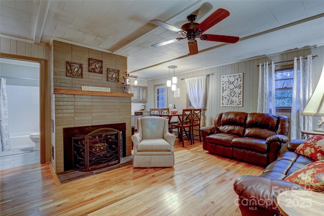 living room featuring crown molding, a fireplace, light hardwood / wood-style floors, and ceiling fan