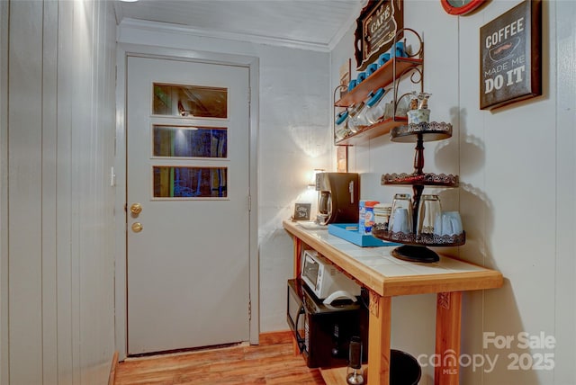 doorway to outside featuring crown molding and light hardwood / wood-style floors