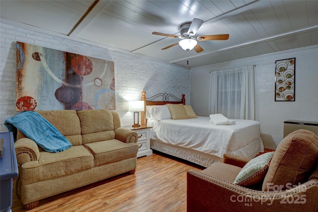 bedroom featuring ceiling fan, brick wall, and hardwood / wood-style floors