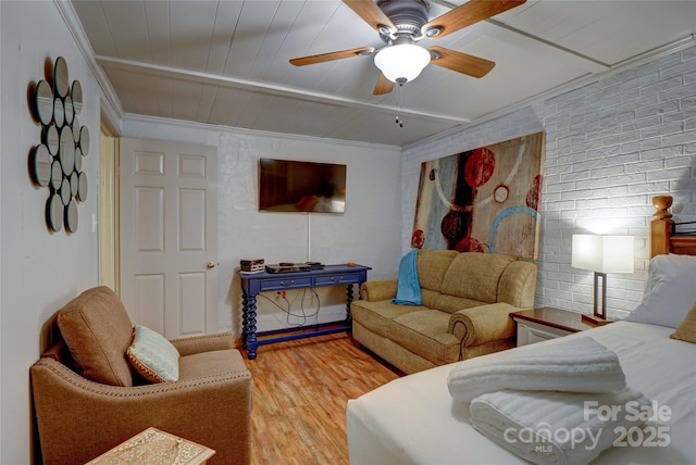 living room with wood-type flooring, ornamental molding, ceiling fan, and brick wall