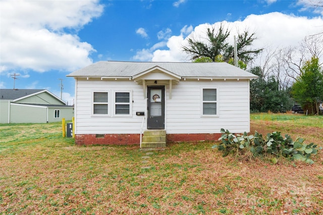 bungalow-style house with entry steps, a front lawn, and crawl space