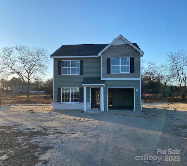 view of front of home with a garage, roof with shingles, and driveway