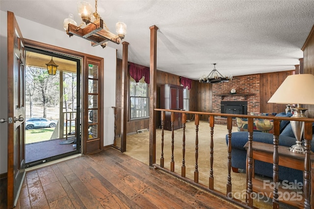 foyer entrance with an inviting chandelier, wooden walls, a wealth of natural light, and dark hardwood / wood-style flooring