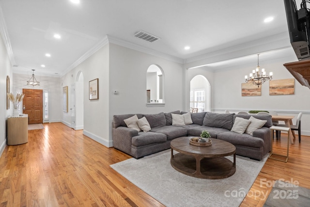 living room featuring ornamental molding, a chandelier, and light hardwood / wood-style flooring