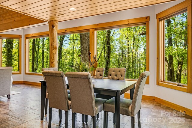 sunroom featuring stone tile floors, baseboards, and a healthy amount of sunlight