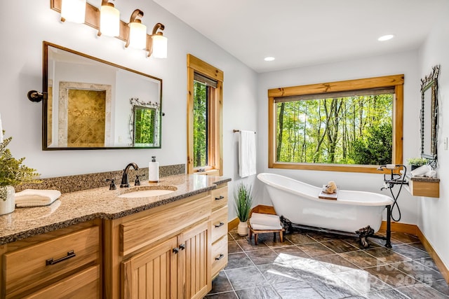 full bath with recessed lighting, baseboards, a soaking tub, and vanity
