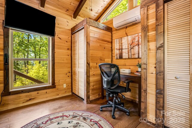 office space featuring wood ceiling, a wall unit AC, hardwood / wood-style flooring, wooden walls, and vaulted ceiling with beams