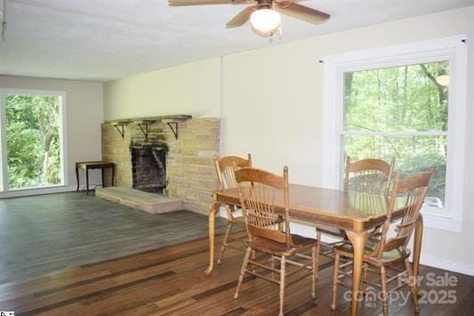 dining area with dark wood-type flooring, a fireplace, and ceiling fan