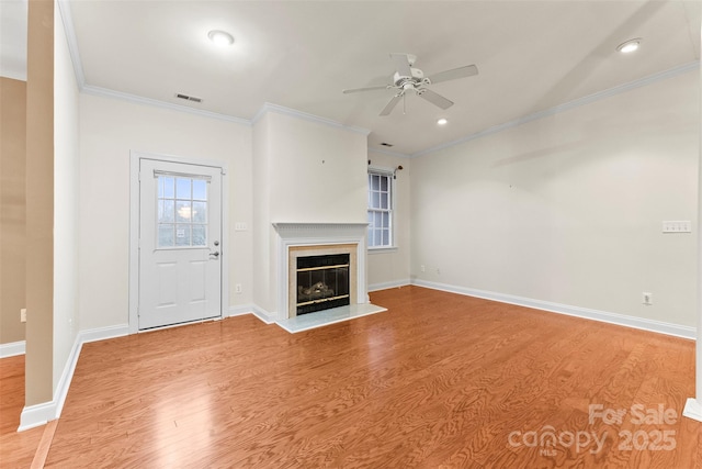 unfurnished living room with crown molding, ceiling fan, a fireplace, and light hardwood / wood-style floors