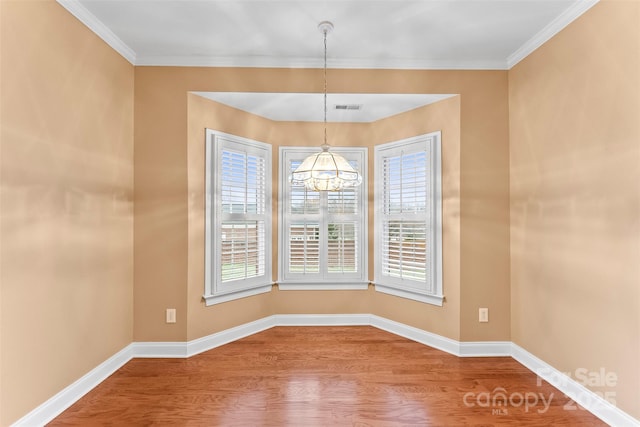 unfurnished dining area featuring an inviting chandelier, ornamental molding, hardwood / wood-style floors, and a wealth of natural light